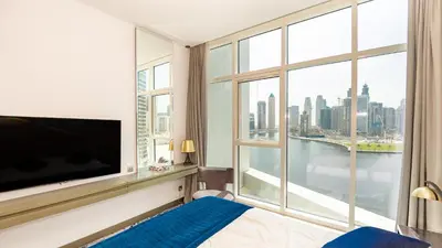 a bedroom with a large tv and a large window at Sleek Studio in Business Bay with Canal View Business Bay, Dubai in Dubai