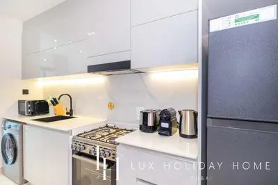 a white kitchen with a stove and a refrigerator at LUX The Modern Binghatti Canal Suite in Dubai