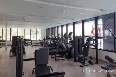 a gym with rows of treadmills and elliptical machines at LUX The Modern Binghatti Canal Suite in Dubai
