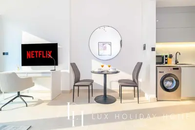 a living room with a tv and a table and chairs at LUX The Modern Binghatti Canal Suite in Dubai