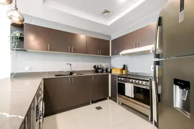 a kitchen with stainless steel appliances and brown cabinets at Charming 2BR + kid's room w/ Marina yacht view in Dubai