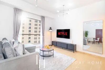 a living room with a couch and a tv at LUX The JBR Marina View Suite 2 in Dubai