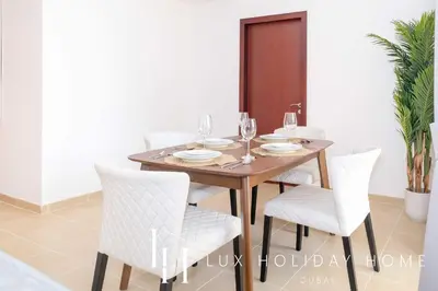 a dining room with a wooden table and white chairs at LUX The JBR Marina View Suite 2 in Dubai