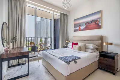 a bedroom with a bed and a desk and a balcony at GuestReady - A prime stay in Creek Harbour in Dubai