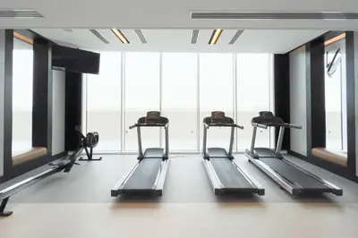 a row of treadmills in a gym with windows at GuestReady - A prime stay in Creek Harbour in Dubai