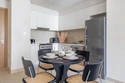 a kitchen with a table with chairs and a refrigerator at GuestReady - A prime stay in Creek Harbour in Dubai