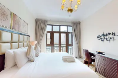 a white bedroom with a large bed and a desk at Souq Al Bahar - One Bed with Dubai Fountain View in Dubai
