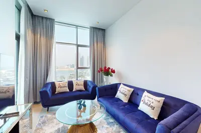 a living room with a blue couch and a glass table at 15 Northside Tower 2 - Charming One Bedroom in Dubai