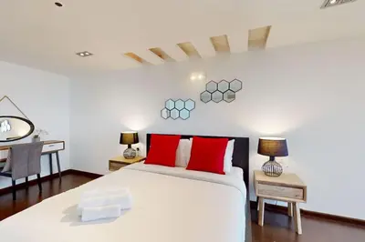 a bedroom with a white bed with red pillows and a desk at Bahar 1 - Opulent Three Bedroom in Dubai