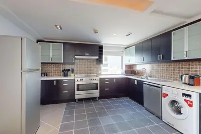 a kitchen with black cabinets and a washer and dryer at Bahar 1 - Opulent Three Bedroom in Dubai