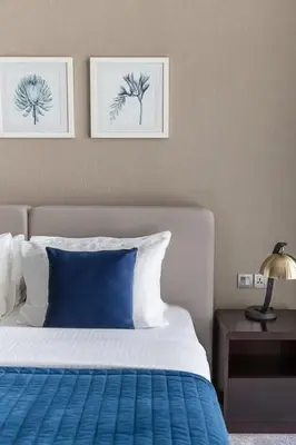 a bedroom with a bed with a blue blanket and two pictures at Frank Porter - DAMAC Prive in Dubai