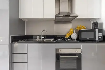 a kitchen with white cabinets and a sink and a microwave at Frank Porter - DAMAC Prive in Dubai