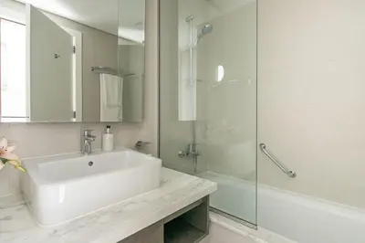 a white bathroom with a sink and a shower at Frank Porter - DAMAC Prive in Dubai