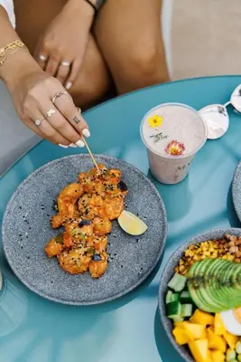 a person eating food on a table with a plate of food at Frank Porter - DAMAC Prive in Dubai