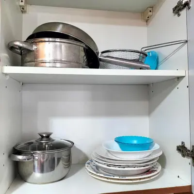 a kitchen shelf with dishes and pots and pans at Private Studio Apartment in Tecom next to Metro station in Dubai