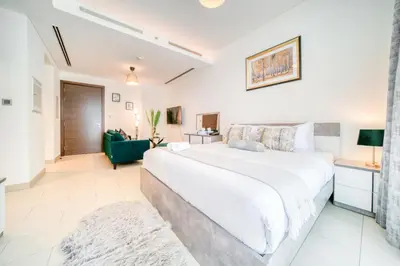 a bedroom with a large white bed and a green couch at Luxury Studio in Sobha Hartland Greens by PK Holidays in Dubai