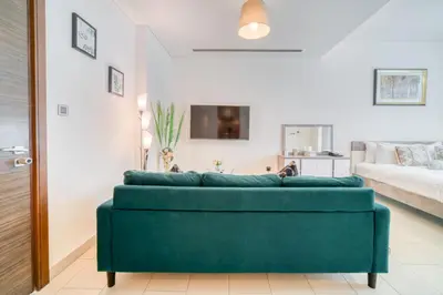 a living room with a green couch in a room at Luxury Studio in Sobha Hartland Greens by PK Holidays in Dubai