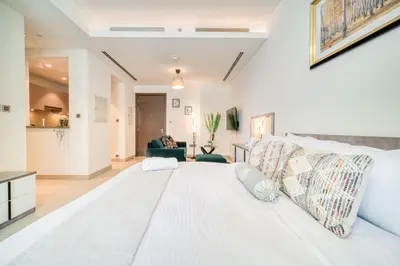 a bedroom with a large white bed in a room at Luxury Studio in Sobha Hartland Greens by PK Holidays in Dubai