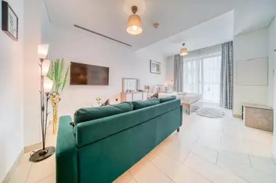 a living room with a green couch in a room at Luxury Studio in Sobha Hartland Greens by PK Holidays in Dubai