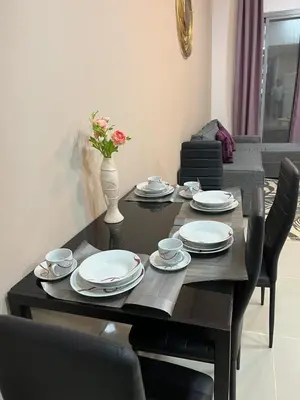 a dining room table with plates and a vase with flowers at SEASONING STAY AT DUBA MARINA in Dubai