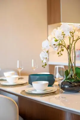 a table with plates and glasses and white flowers on it at Hotel Apartment Near Burj Khalifa - Opera T2 - شقة فندقية قريبة من برج خليفة اوبرا -برج 2 in Dubai