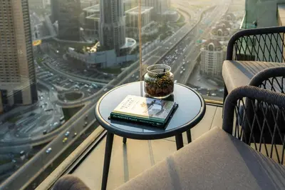 a book on a table on a balcony with a view of a city at Ultimate Stay Full Burj Khalifa & Downtown Views Designer Luxury High Floor connected to Dubai Mall for 4 People in Dubai