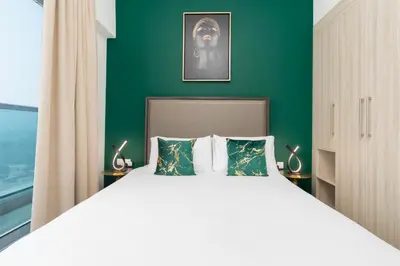 a bedroom with a large bed with a green wall at The Elite Apartment in Dubai
