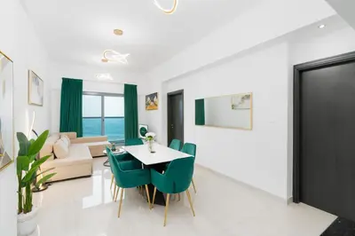 a dining room and living room with a table and chairs at The Elite Apartment in Dubai