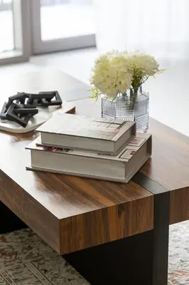 a stack of books on a table with a vase of flowers at Frank Porter - Summer at Creek Beach in Dubai