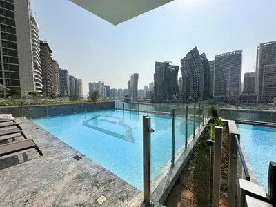 a large swimming pool with a city skyline in the background at Trophy - Santorini Studio BurjKhalifa & Canal Views Sofa Bed in Dubai