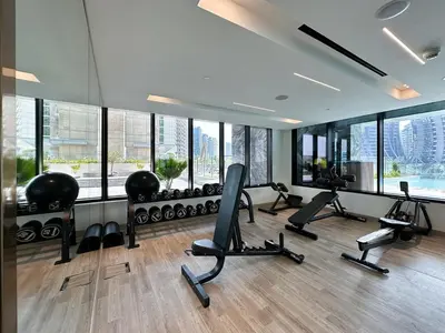 a gym with treadmills and ellipticals in a room with windows at Trophy - Santorini Studio BurjKhalifa & Canal Views Sofa Bed in Dubai