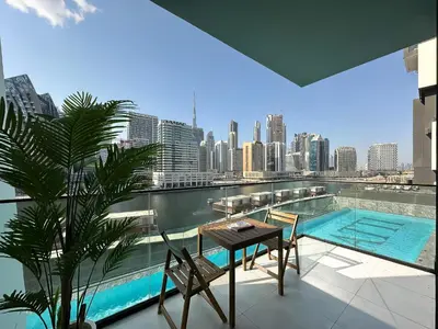 a balcony with a table and chairs and a pool at Trophy - Santorini Studio BurjKhalifa & Canal Views Sofa Bed in Dubai