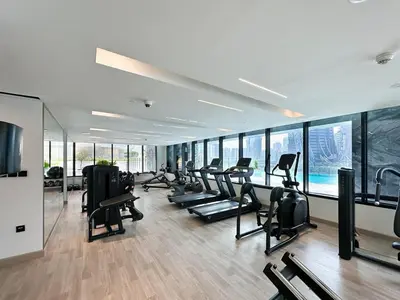 a gym with a row of treadmills and ellipticals at Trophy - Santorini Studio BurjKhalifa & Canal Views Sofa Bed in Dubai