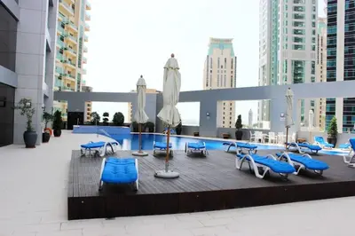 a swimming pool with blue lounge chairs and umbrellas at Very nice studio in Skyview Tower Dubai Marina in Dubai