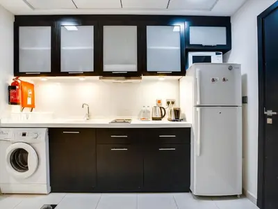 a kitchen with black cabinets and a white refrigerator at Very nice studio in Skyview Tower Dubai Marina in Dubai