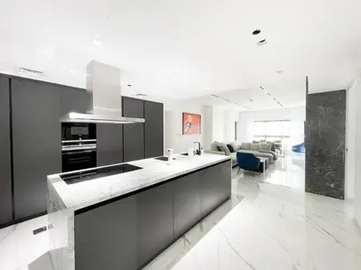 a kitchen with black cabinets and a living room at Palm Jumeirah Paradise- Luxury,Unveiled in Dubai