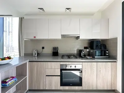 a kitchen with white cabinets and a stove top oven at Trophy - Alfresco 2BDR Suite in Dubai
