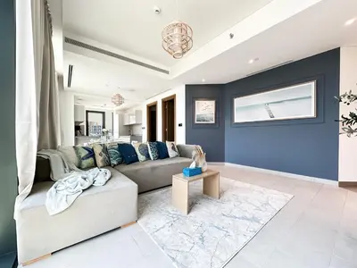a living room with a couch and a blue wall at Trophy - Alfresco 2BDR Suite in Dubai