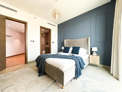 a bedroom with a bed and a blue wall at Trophy - Alfresco 2BDR Suite in Dubai