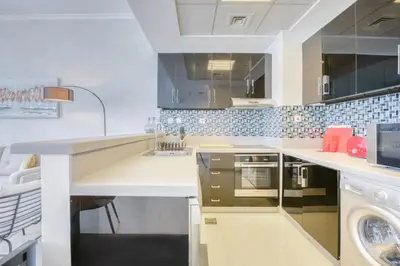 a white kitchen with a sink and a dishwasher at Spacious 1BR in Botanica tower with sea view by PK holidays in Dubai