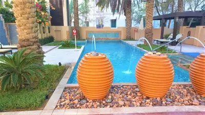 a swimming pool with three large orange vases next to it at Spacious 2Bedroom with Burj View in Downtown Dubai in Dubai