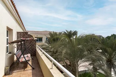 a balcony with palm trees on a house at Lake Apartments - 1BR Apartment - Allsopp&Allsopp in Dubai