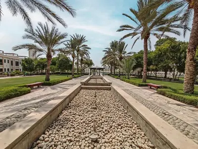 a park with palm trees and benches in a park at Lake Apartments - 1BR Apartment - Allsopp&Allsopp in Dubai