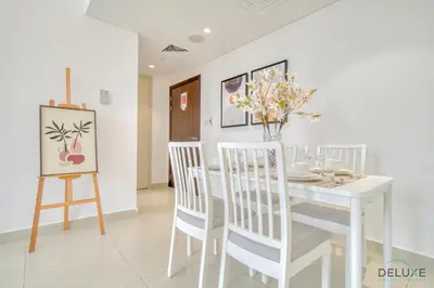 a white dining room with a white table and chairs at Serene 1BR at Afnan 3 Midtown Dubai Production City by Deluxe Holiday Homes in Dubai
