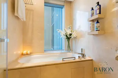 a bathroom with a bath tub with a vase of flowers at The Refined in Dubai