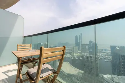 a table and chair on a balcony with a view at Lux BnB Upper Crest Tower I Skyline Views in Dubai