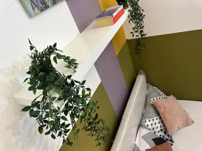 a shelf on a wall with plants next to a couch at Double window Partition Room in Tecom Near Metro in Dubai