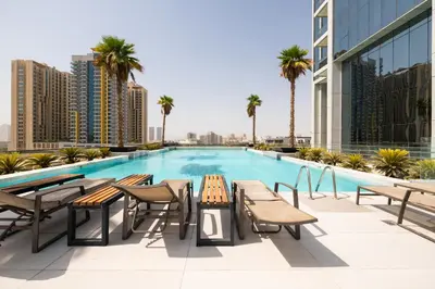 a swimming pool with tables and chairs on a building at Daniels Cozy Studio at JVC in Dubai