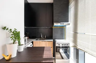a kitchen with black cabinets and a sink and a stove at Daniels Cozy Studio at JVC in Dubai