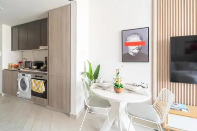 a kitchen with a white table and chairs in a room at Frank Porter - Oxford 212 in Dubai